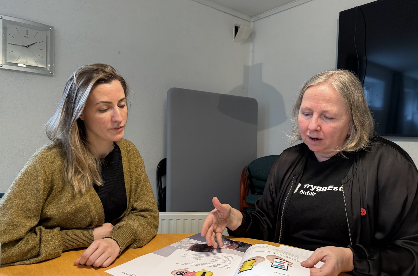To kvinner som ser på en brosjyre om TryggEst