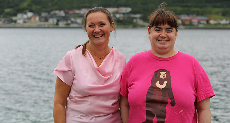Bilde av to damer som ser mot kameraet og smiler. Bildet er tatt utendørs. Copyright Linda Barøy 
