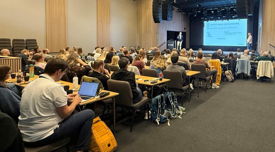 Bildet viser flere personer som sitter i en forelesningssal.