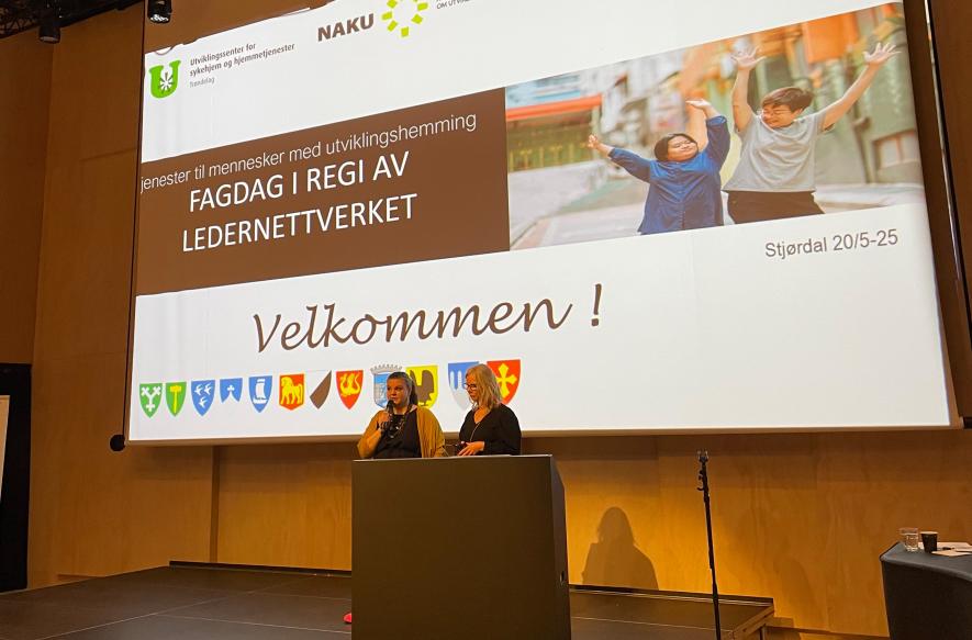 Bilde av to personer som står på en scene  