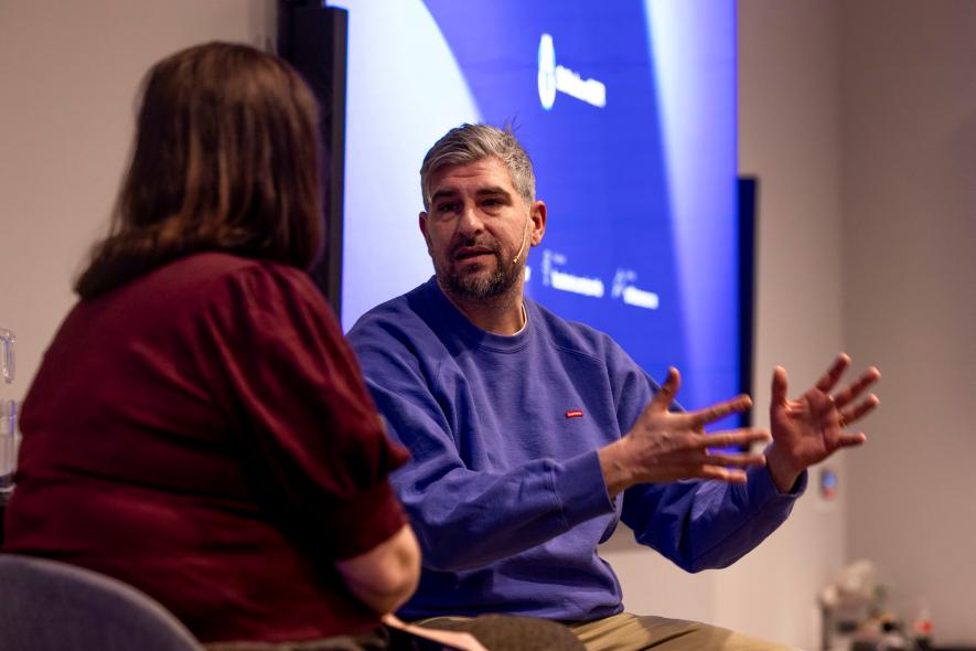 Bildet viser en mann og en k\vinne siom sitter på en konferansescene og snakker sammen.