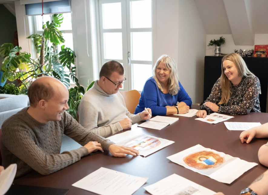 Noen av forfatterne sitter rundt et bord og snakker sammen