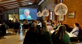 Bildet viser personer som sitter i et rom og ser film på en storskjerm