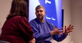 Bildet viser en mann og en k\vinne siom sitter på en konferansescene og snakker sammen.