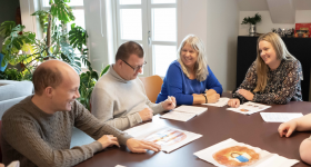 Noen av forfatterne sitter rundt et bord og snakker sammen